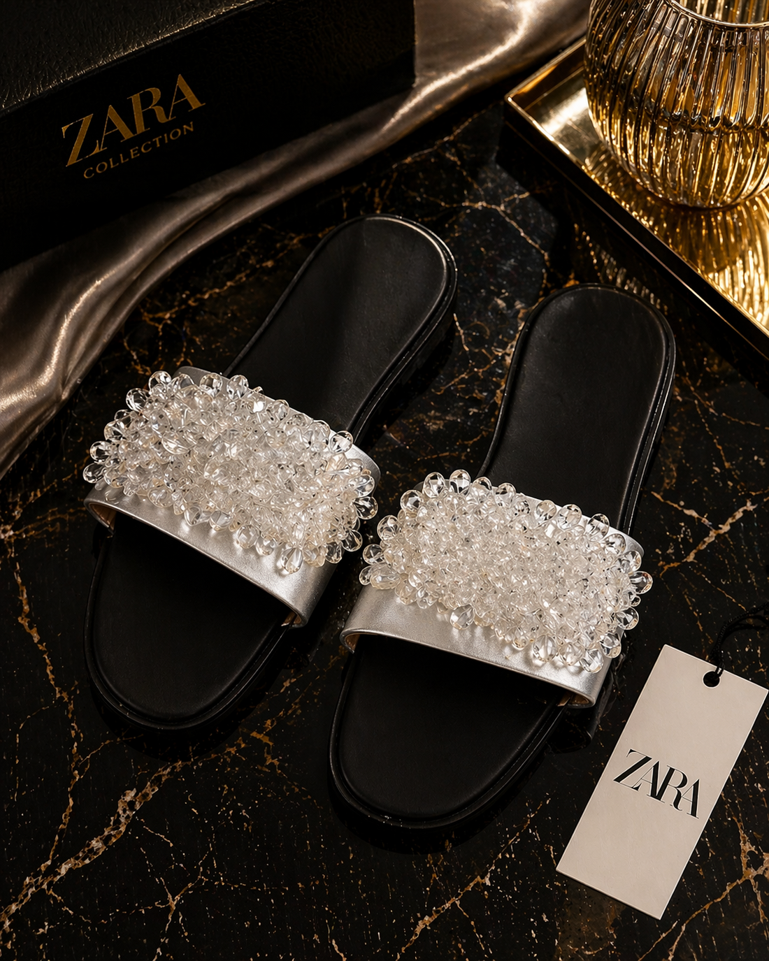 Black slides with orange gemstones on a Zara branded surface
