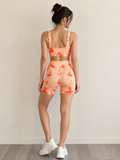 Woman wearing an orange tie-dye athletic outfit on a plain background