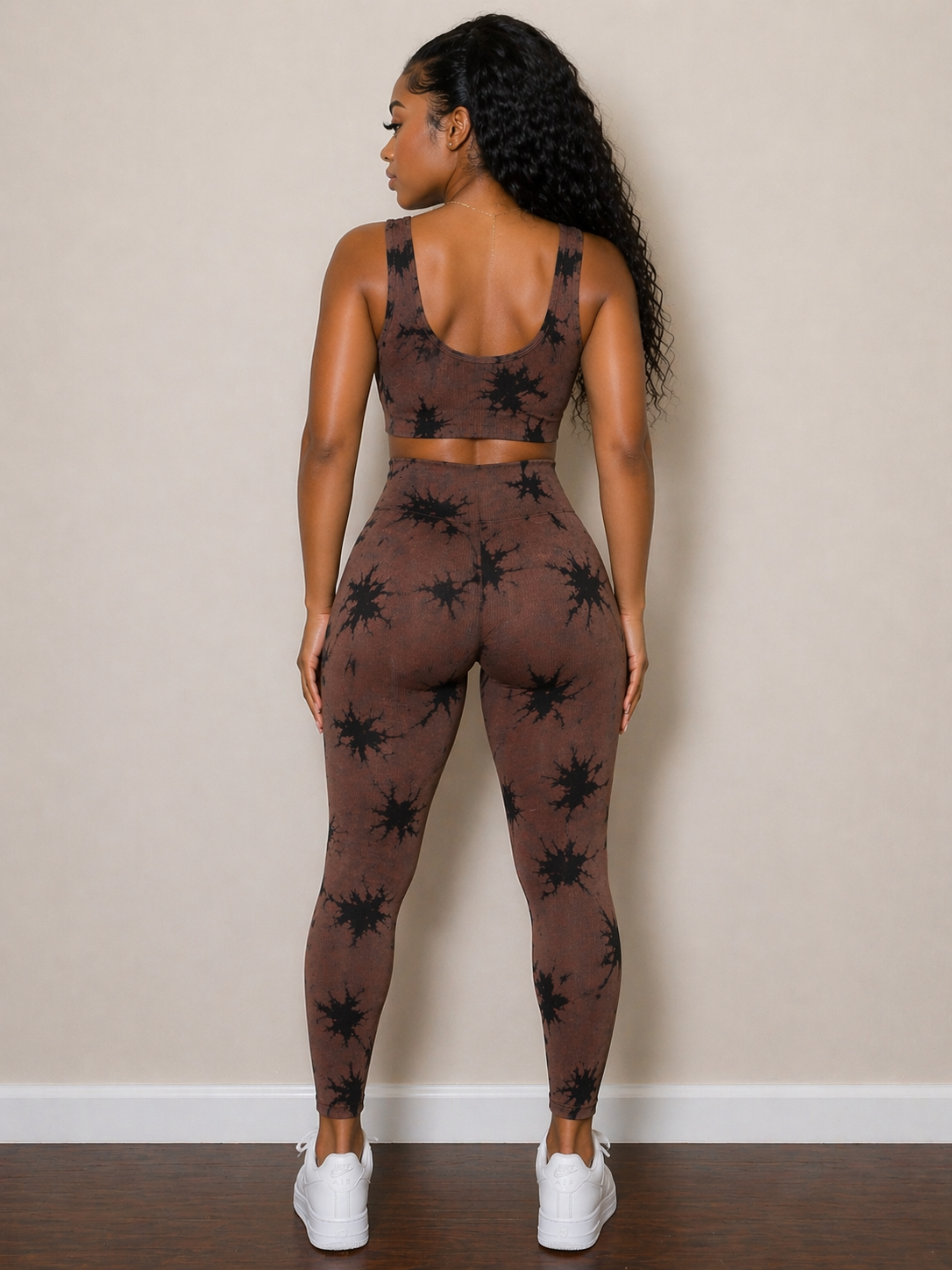 Person wearing a brown patterned sports bra and leggings set against a beige wall.