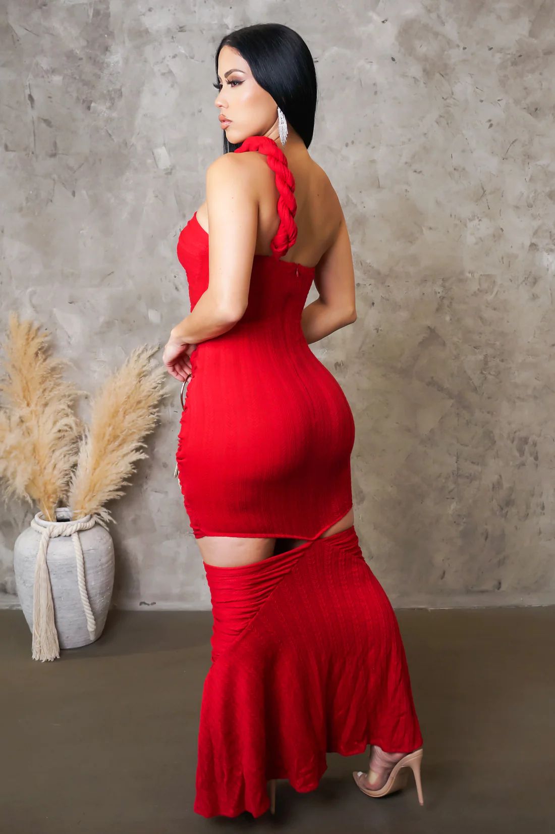 Woman wearing a red dress with a textured wall and potted plant in the background