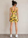 Woman wearing a yellow and black tie-dye sports bra and shorts set on a plain background