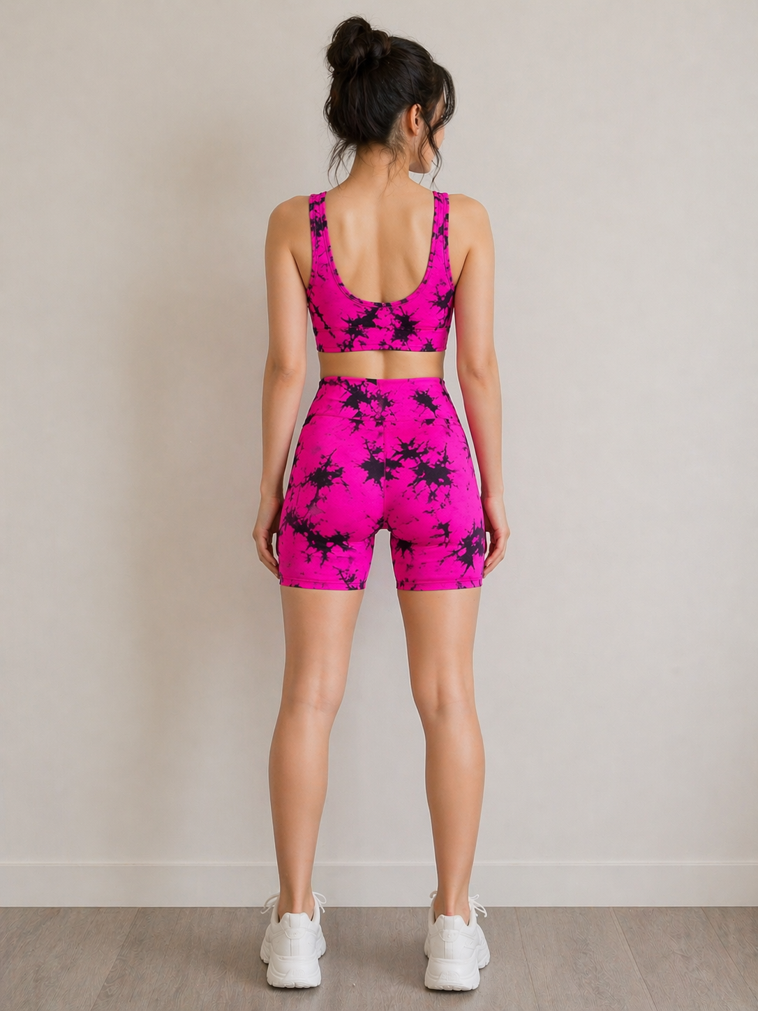Woman wearing a pink and black floral sports outfit against a plain background