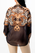 Sheer blouse with intricate gold and black pattern on a white background