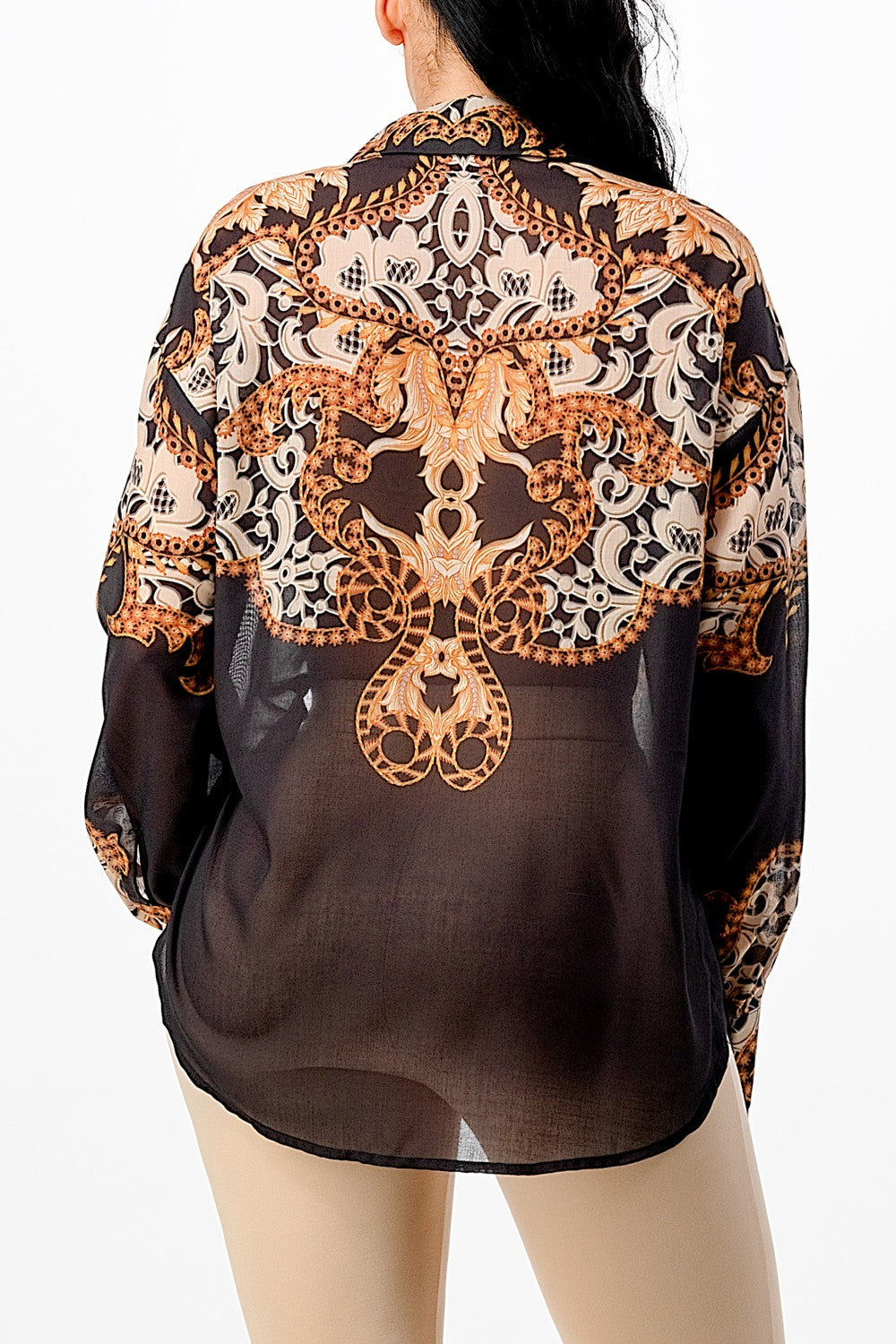 Sheer blouse with intricate gold and black pattern on a white background