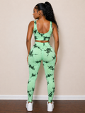 Woman wearing a green and black patterned jumpsuit against a beige wall.