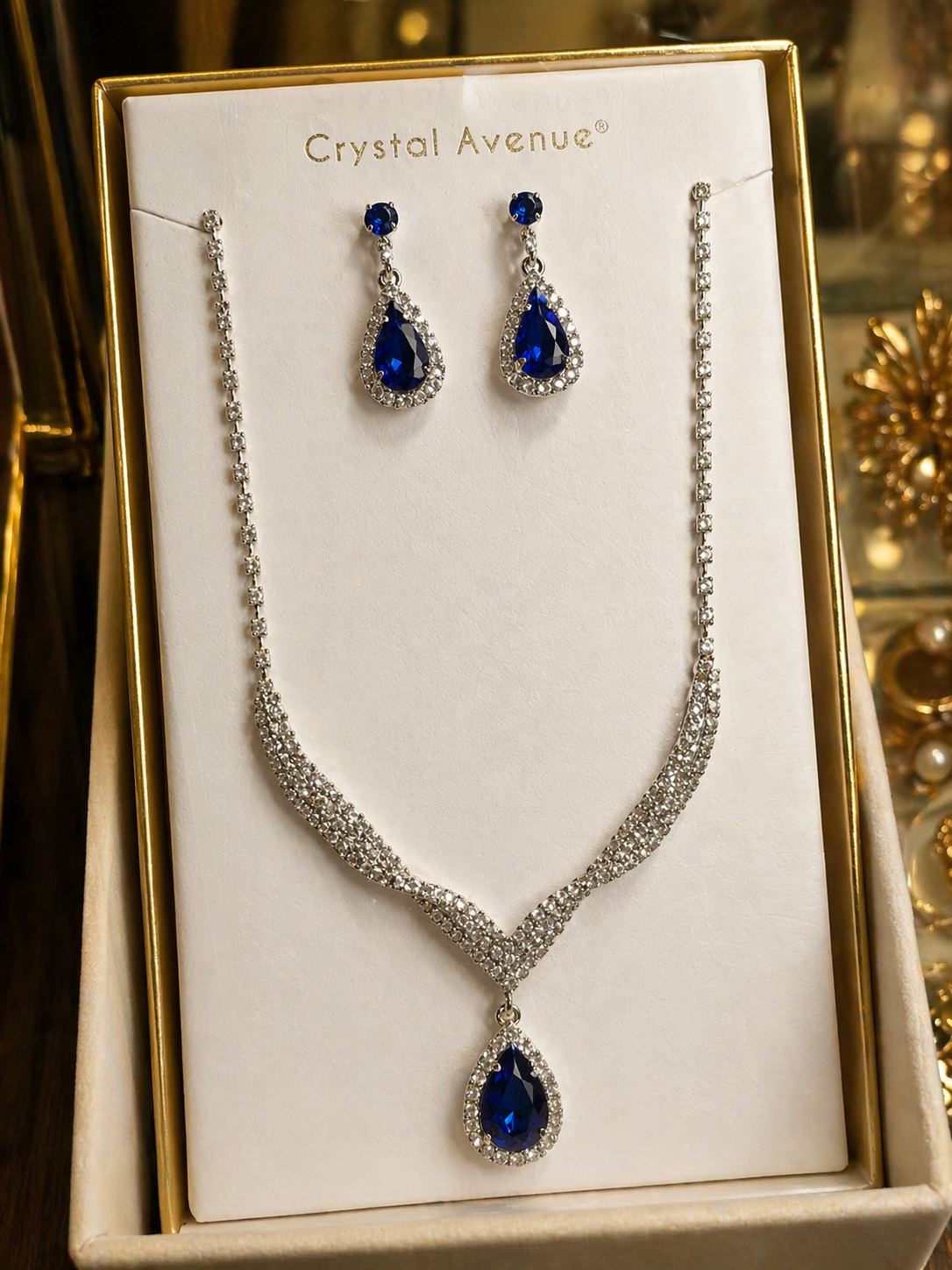 Jewelry set with necklace and earrings featuring blue stones on a Crystal Avenue branded card.