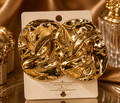 Gold earrings on a branded card with a gold background