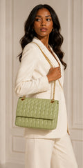 Woman holding a green quilted handbag against a neutral background