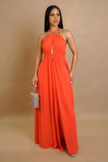 Woman wearing an orange halter neck maxi dress against a beige background