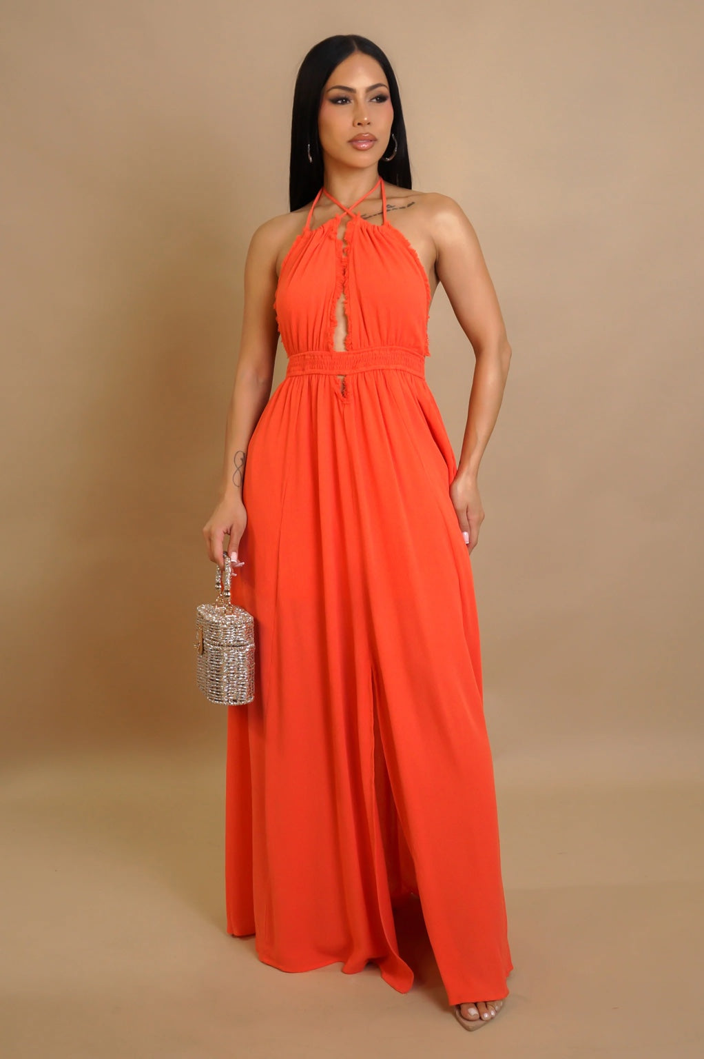 Woman wearing an orange halter neck maxi dress against a beige background