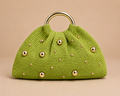 Green knitted handbag with gold studs on a beige background