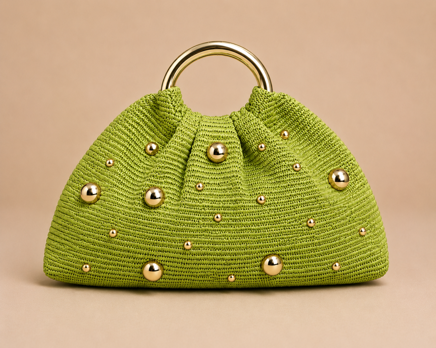 Green knitted handbag with gold studs on a beige background