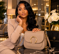 “Woman resting hand on beige Luxe Maison leather crossbody bag with gold hardware in elegant setting”
