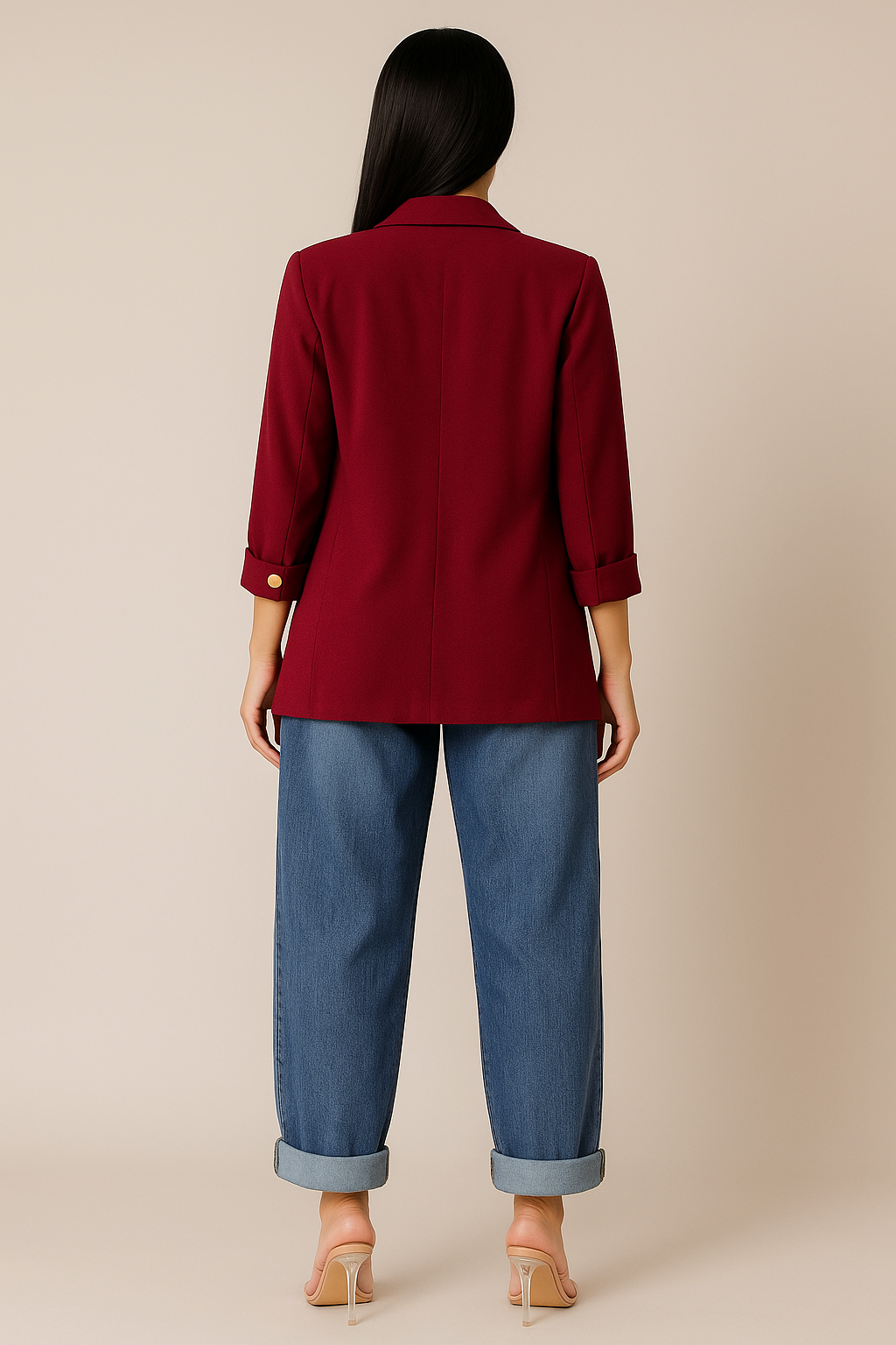 Person wearing a red blazer and blue jeans against a beige background