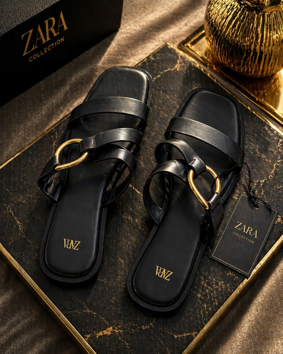 Black sandals with gold accents on a Zara branded surface