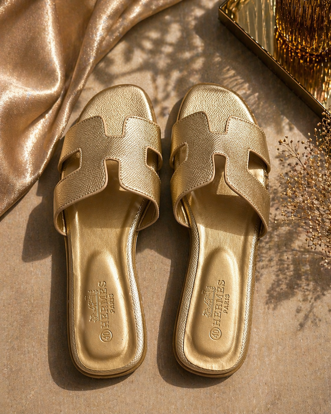 Gold sandals with cut-out design on a gold fabric background
