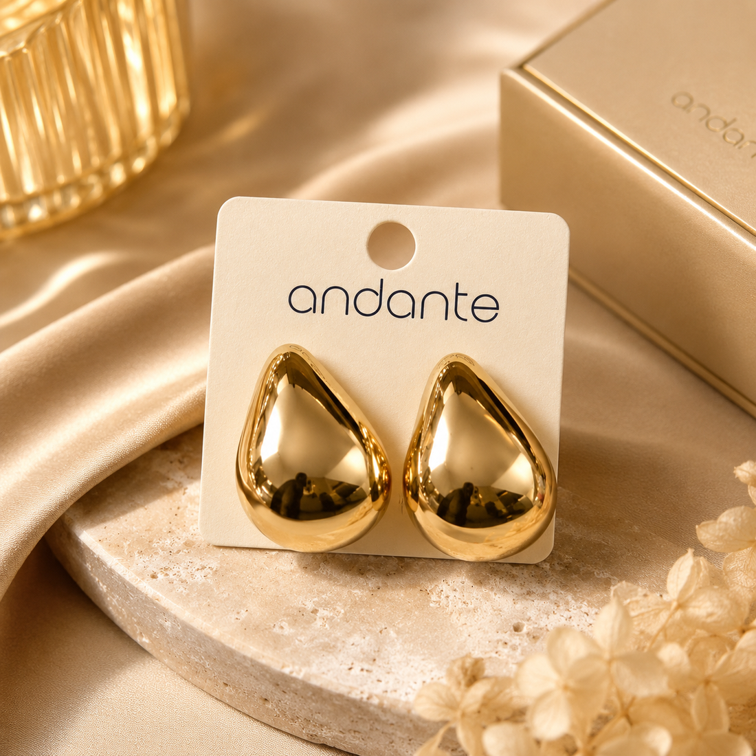 Gold teardrop earrings on an 'andante' branded card with a beige background