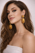 Woman wearing gold earrings with a plain background
