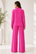 Woman wearing a pink pajama set in a minimalistic room.