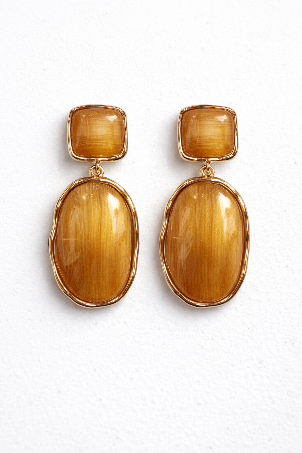 Woman wearing gold earrings with a plain background