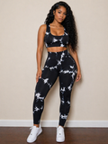 Woman wearing a black and white patterned sports bra and leggings set against a beige wall.