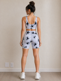 Woman wearing a white athletic outfit with black patterns in a room.