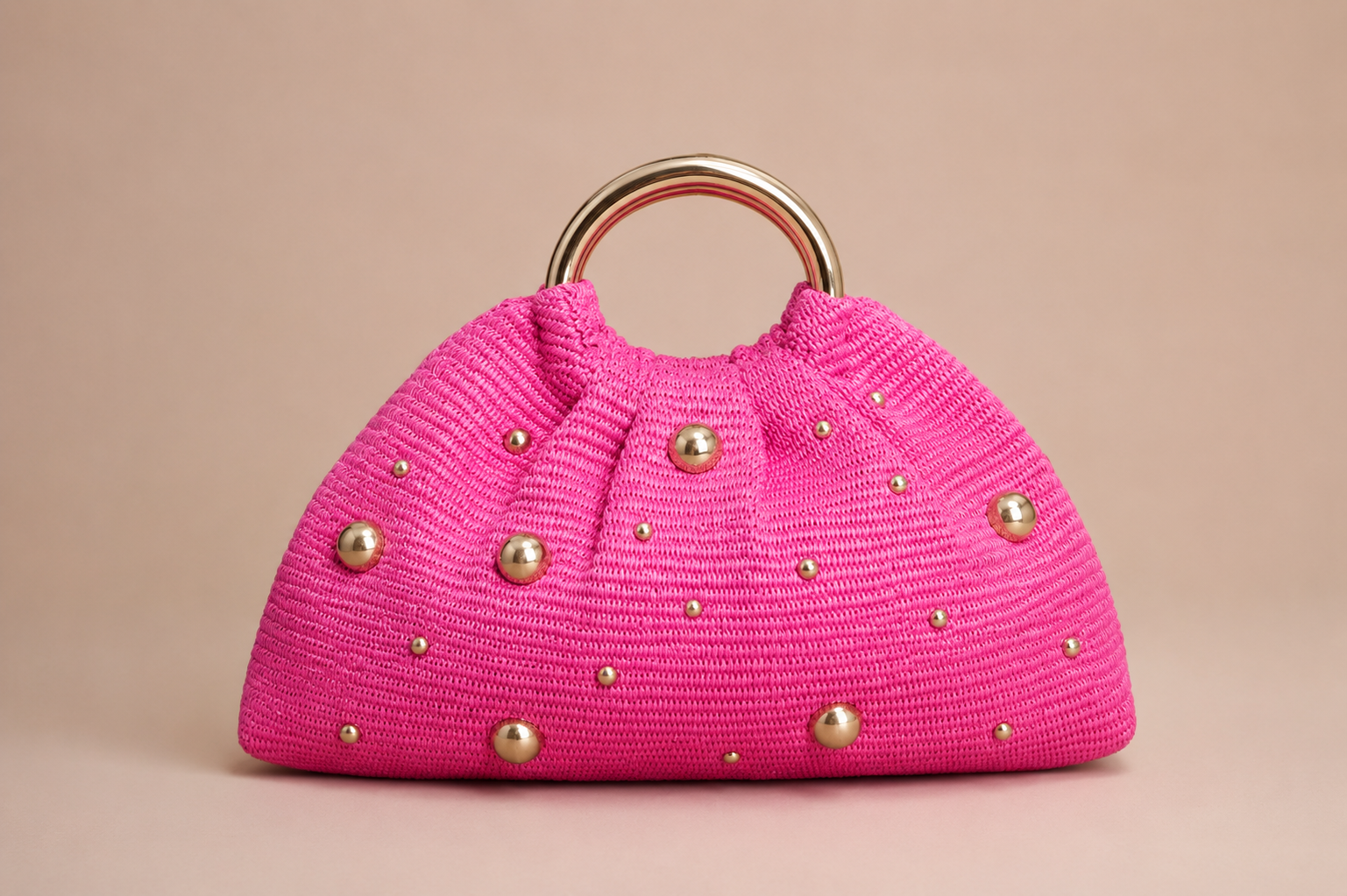Pink handbag with gold studs on a beige background