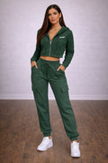 Woman wearing a green tracksuit with 'SPORT' branding on a wooden floor.