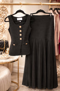 Black vest and pleated skirt on hangers with a blurred background of a store setting.