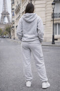 Person wearing a gray tracksuit standing on a street with the Eiffel Tower in the background