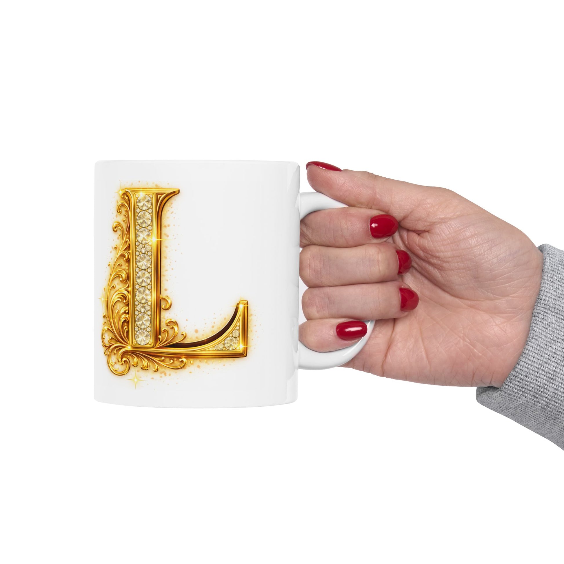 Hand holding a mug with a decorative gold letter 'L' on a white background