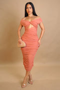 Woman wearing a coral off-shoulder dress with cut-out design on a beige background
