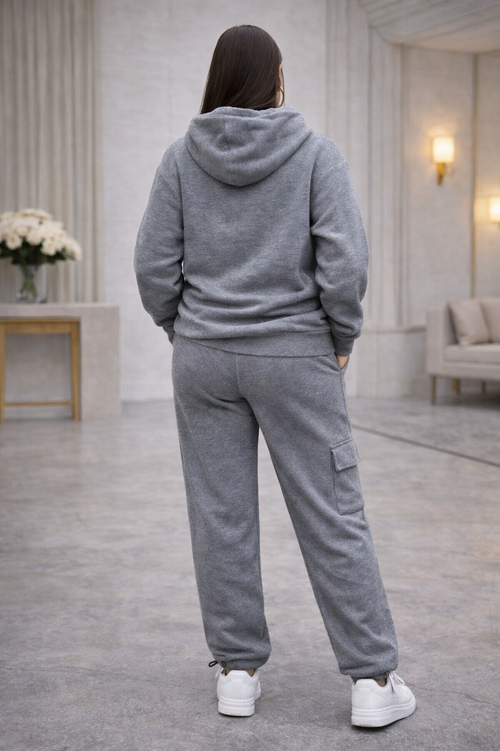 Person wearing a gray tracksuit in a room with light-colored walls and decor.