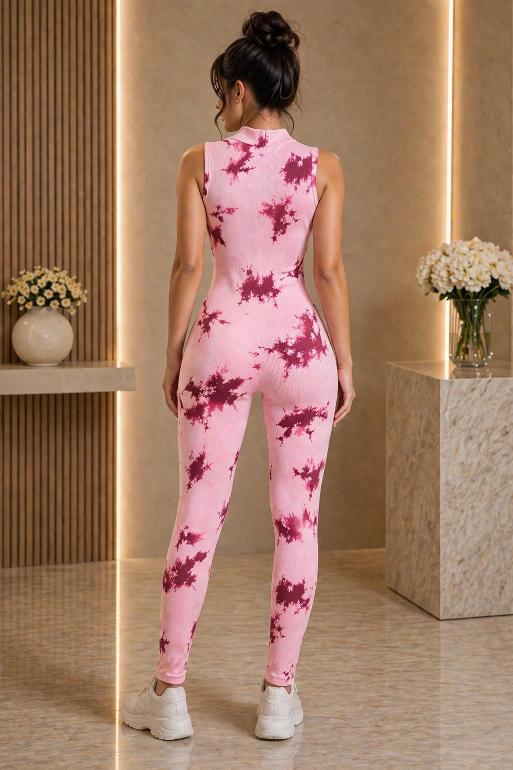 Woman wearing a pink tie-dye jumpsuit in an indoor setting with decorative elements.