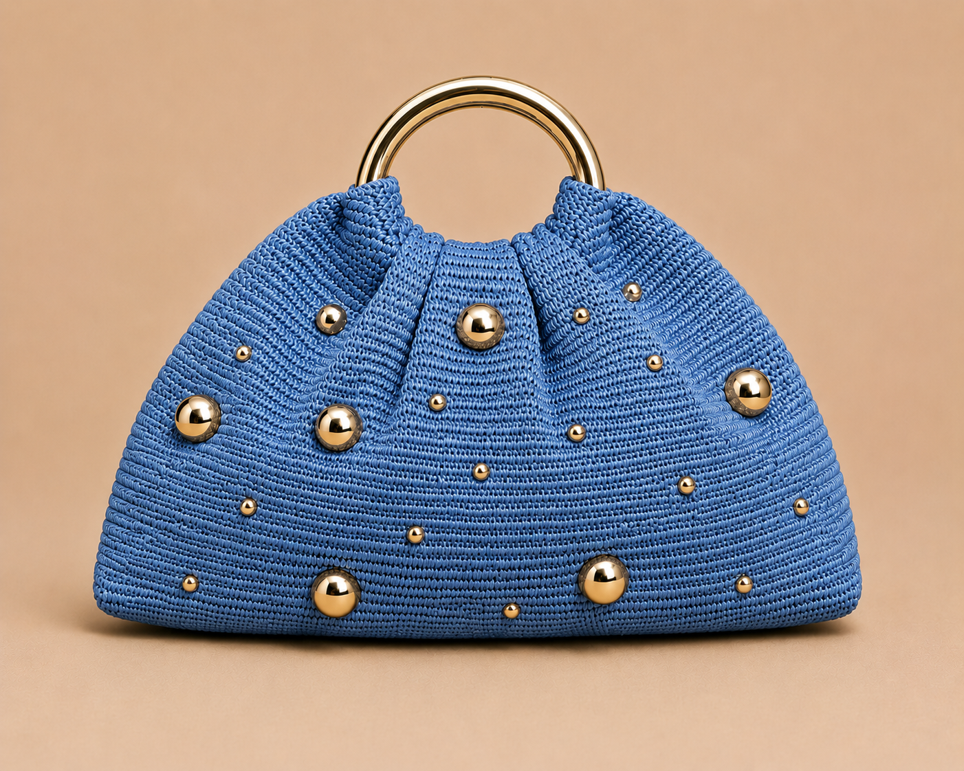 Blue handbag with gold studs on a beige background