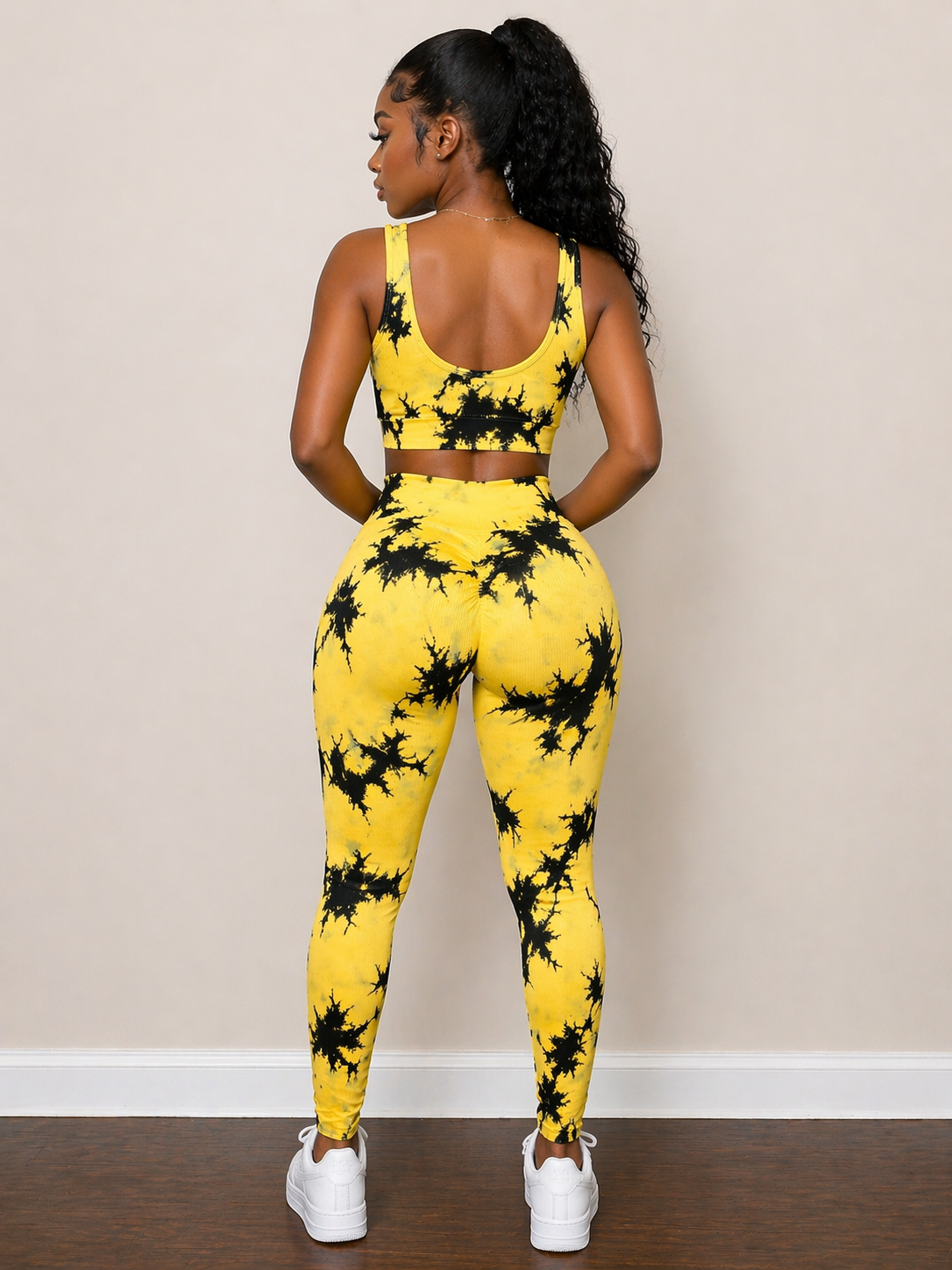 Woman wearing a yellow and black patterned outfit against a beige wall.