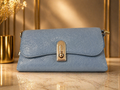 Blue handbag with gold accents on a reflective surface