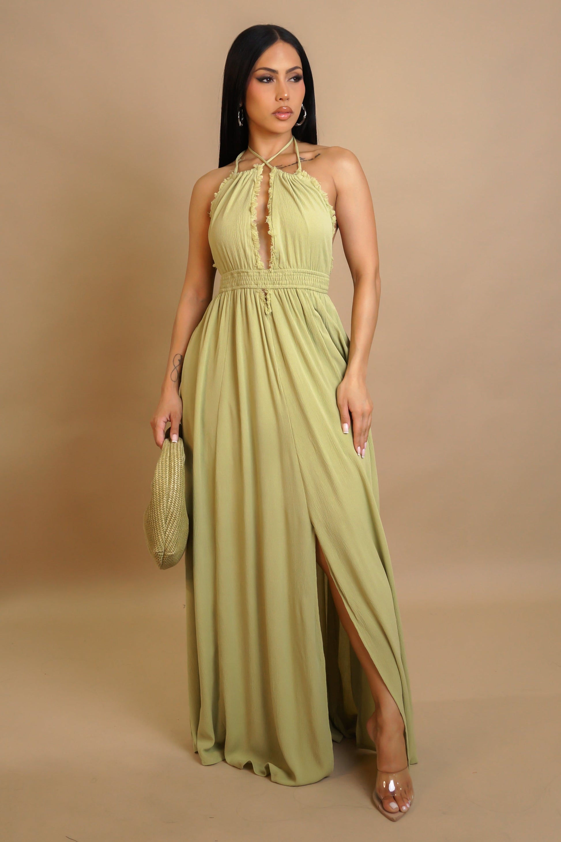 Woman wearing a long green dress against a beige background