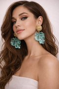 Woman wearing large green leaf-shaped earrings with a plain background