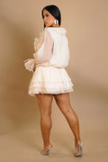 Woman wearing a white ruffled outfit against a beige background