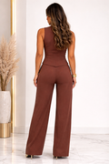 Woman wearing a brown jumpsuit in a minimalistic room with decorative elements.