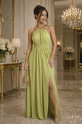 Woman in a green dress standing in an elegant room with chandeliers and floral arrangements.