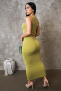 Woman wearing a green ribbed dress against a gray concrete wall.