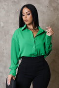 Woman wearing a green blouse and black pants against a neutral background