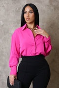 Woman wearing a bright pink shirt and black pants against a gray background