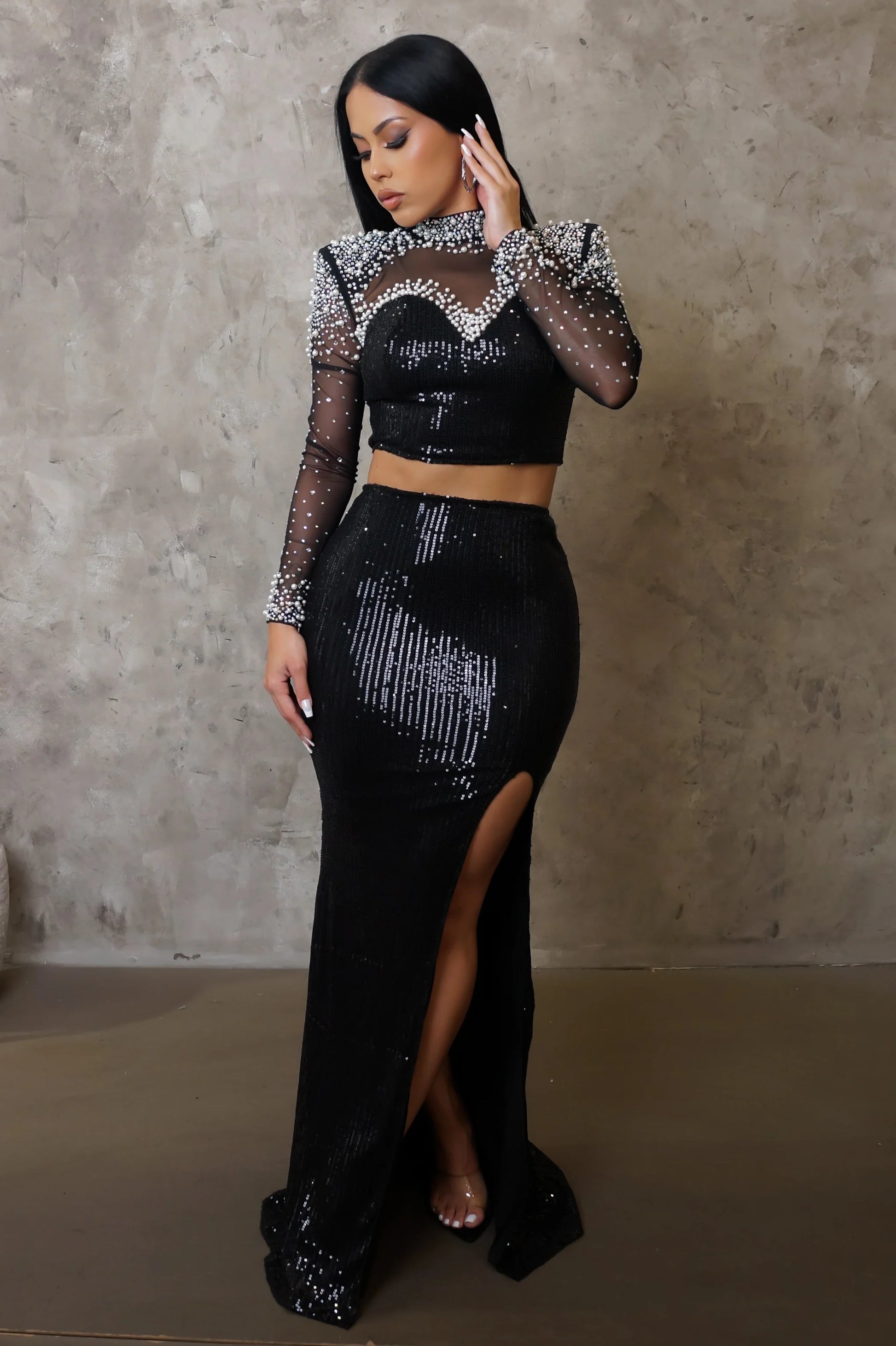 Woman wearing a black and silver dress with a high slit against a neutral background