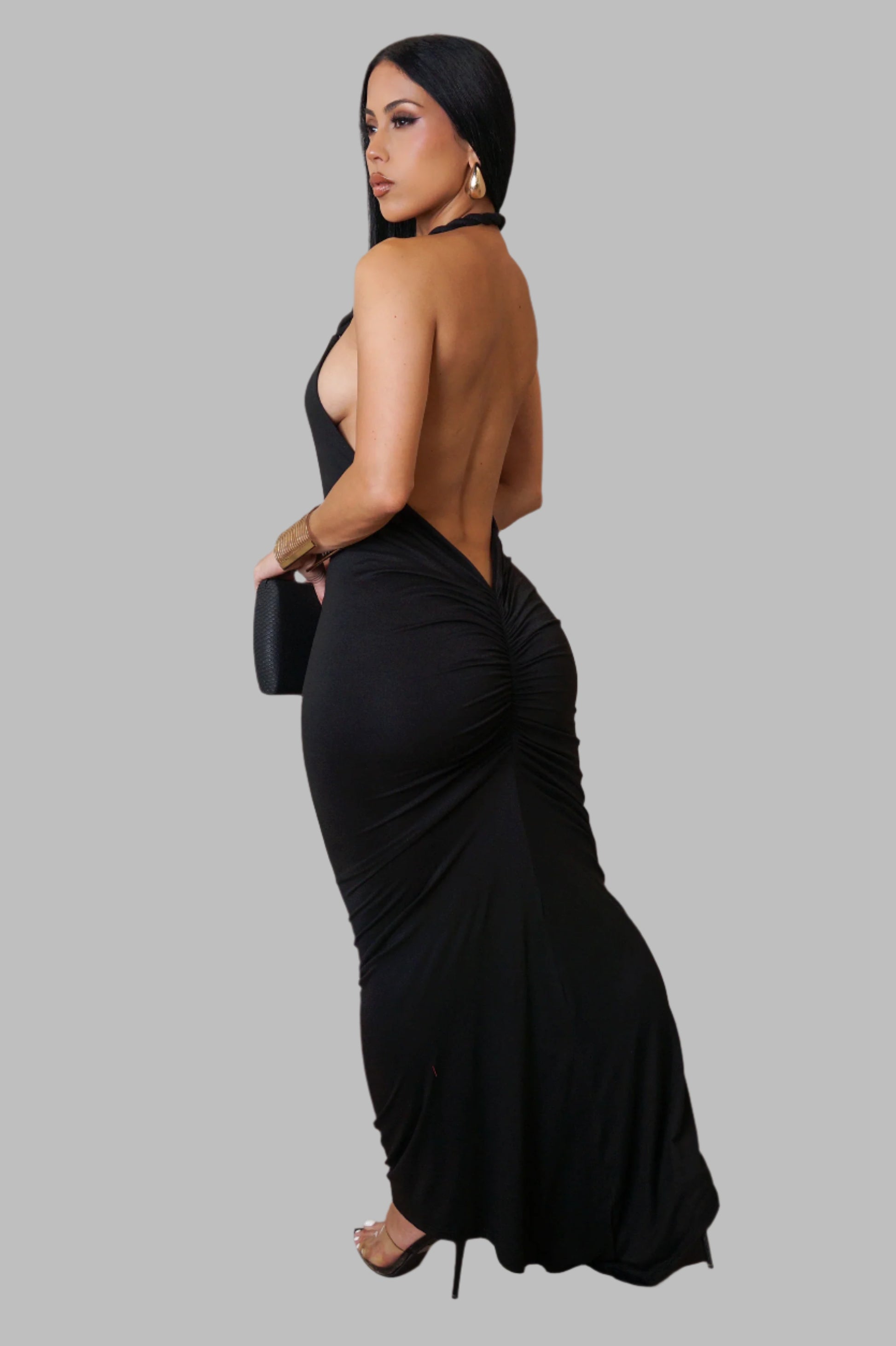 Woman wearing a black evening gown with a high slit on a gray background