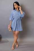 Woman wearing a blue denim dress against a gray background