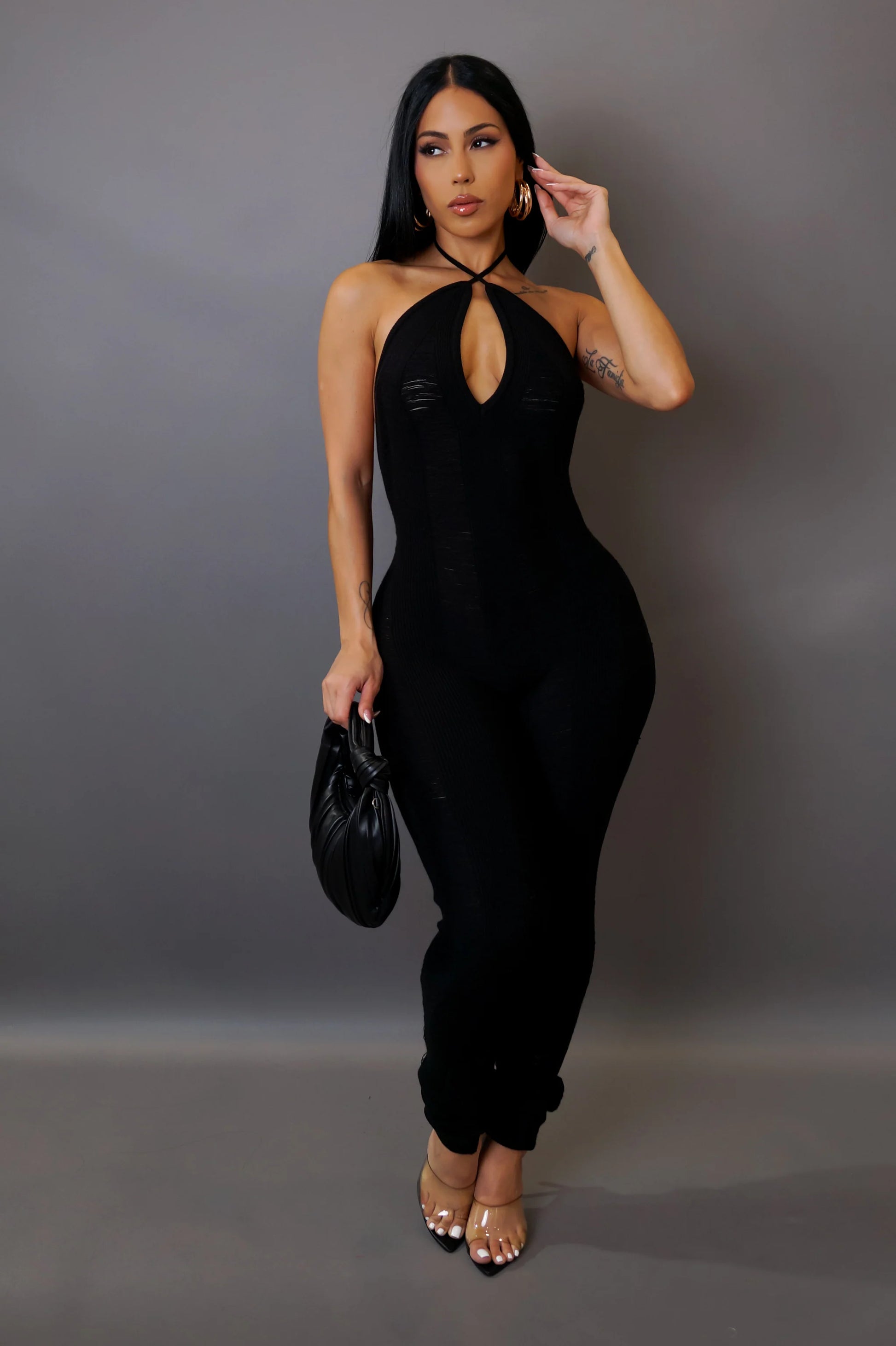 Woman wearing a black jumpsuit against a gray background
