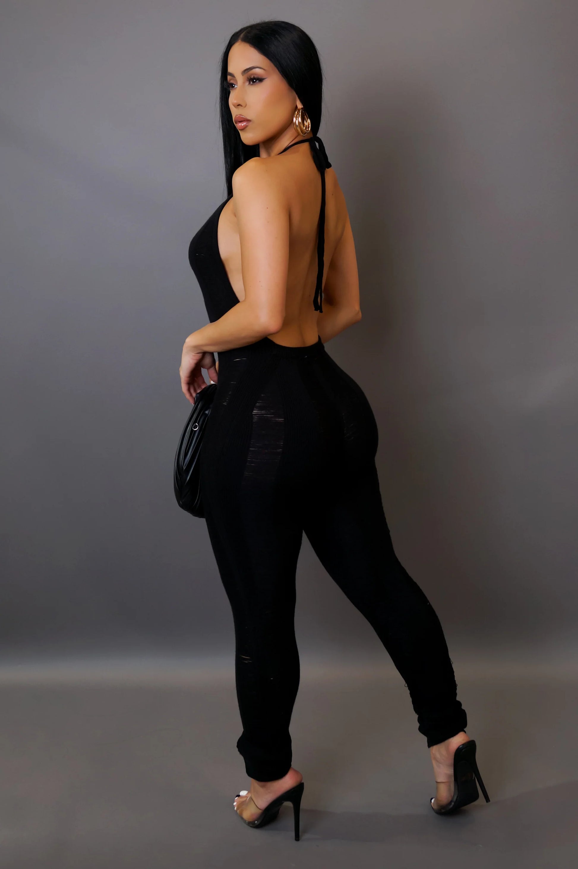Woman wearing a black outfit with a high slit on a gray background
